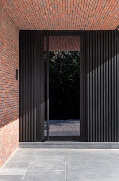 an open door to a brick building with black slats on the walls and floor