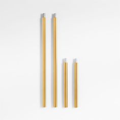 three gold and silver metal straws on a white surface