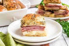 ham and cheese sliders on white plates with parsley sprinkled in black sesame seeds