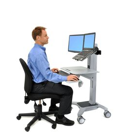 a man sitting in front of a computer desk with a monitor and keyboard on it