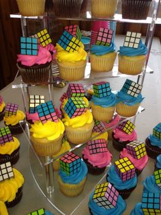 cupcakes with colorful frosting are arranged on a cake stand in front of other cupcakes