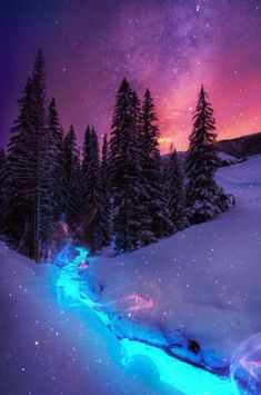 the night sky is lit up with stars and clouds over a snowy mountain stream that runs through it