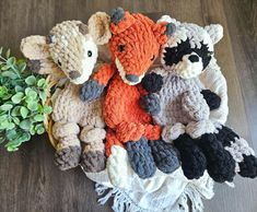 several knitted stuffed animals sitting next to each other on a wooden table with a plant