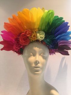 a white mannequin head with multi colored feathers and flowers on it's top