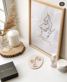 a white table topped with an art piece and a framed drawing on top of it