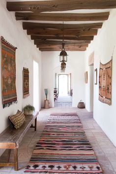 a long hallway with rugs on the floor and wooden benches in front of it