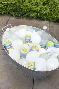 a bucket filled with lots of bottles of water next to a sidewalk on top of cement