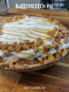 there is a pie on the table with white frosting and peanut butter toppings