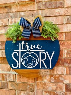 a blue sign that says true story hanging on the side of a brick building with a bow