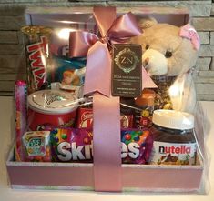 a teddy bear in a pink gift box filled with candy, candies and snacks