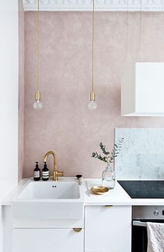 a kitchen with pink walls and gold fixtures