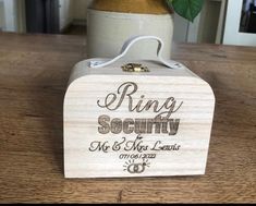 a wooden box with a flower in it sitting on a table next to a potted plant