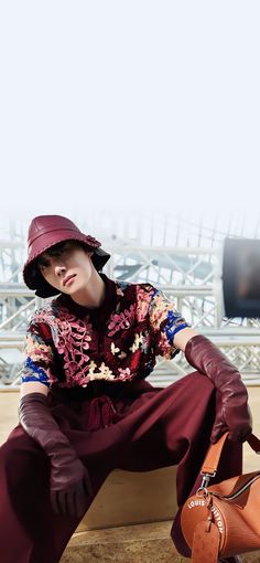 a person sitting on a ledge with a handbag in front of them and a sky background