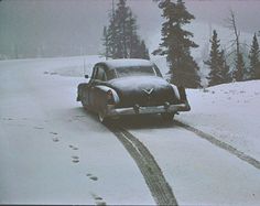 an old car driving down a snowy road