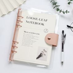 an open notebook sitting on top of a table next to a pen and eyeglasses