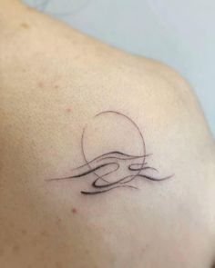 the back of a woman's shoulder with a wave tattoo on it