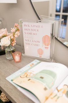 an open book sitting on top of a table next to a vase filled with flowers