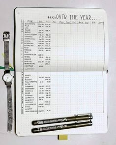 an open notebook with a watch and pen on it