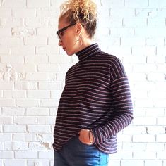 a woman standing in front of a white brick wall with her hands on her hips