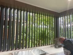 a man standing in front of a window next to a counter with a bird cage on it