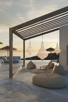 an outdoor seating area with chairs and umbrellas on the beach at sunset or dawn