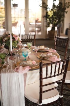 the table is set with plates, silverware and pink napkins for an elegant dinner