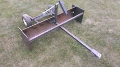 a metal object sitting in the grass on top of it's side with wheels