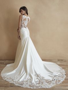 a woman in a wedding dress standing on a wooden floor with her back to the camera