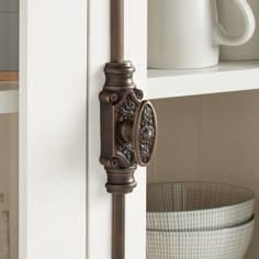 a close up of a door handle on a white cabinet with a basket in the background