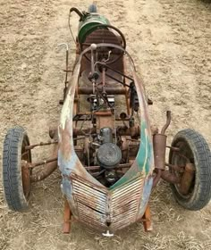 an old, rusted car sitting in the middle of a field with wheels attached to it