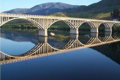 a bridge that is over water with mountains in the background