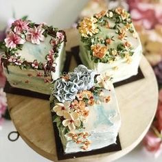 three decorated cakes sitting on top of a wooden table