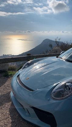 a blue sports car parked on top of a hill