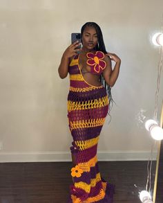 a woman in a crocheted dress taking a selfie with her cell phone