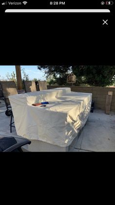 an outdoor table covered with a white tarp in the middle of a patio area