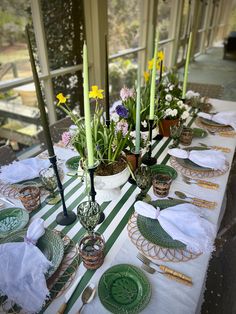 the table is set with green plates and flowers in vases, candles, and napkins