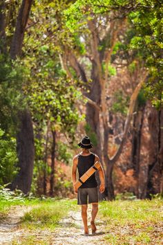 a man walking down a dirt road in the woods