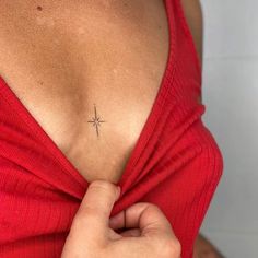 a woman with a cross tattoo on her chest is holding onto the back of her shirt