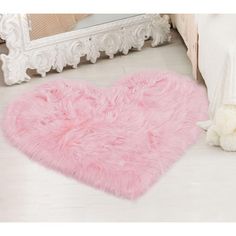 a pink heart shaped rug sitting on top of a floor next to a white teddy bear