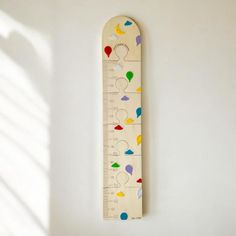 a wooden ruler with different colored shapes and sizes on the bottom, sitting against a white wall