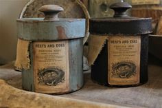 two old fashioned canisters sitting on top of a table