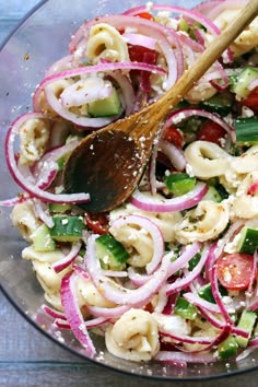 a wooden spoon in a bowl filled with pasta salad