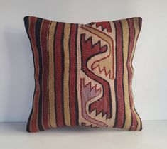 a red, yellow and black pillow sitting on top of a white table next to a wall