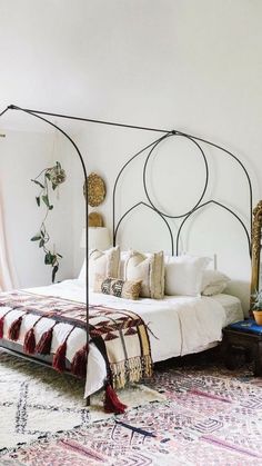 a bedroom with a canopy bed and plants on the side tables in front of it