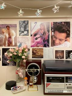 there are many pictures on the wall and a radio next to it with flowers in a vase