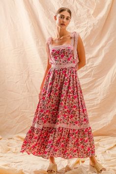 a woman in a floral dress poses for the camera with her hand on her chin