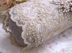 a close up of a pillow on a bed with flowers in the background and lace