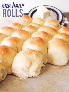 rolls are lined up on a cutting board with butter in the background and text overlay that reads how to make one hour rolls