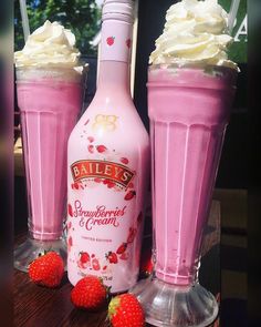 two pink drinks with whipped cream and strawberries