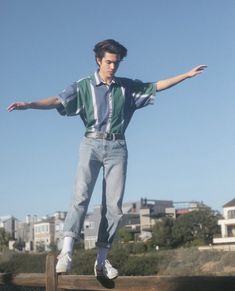 a young man riding a skateboard on top of a wooden rail with his arms outstretched